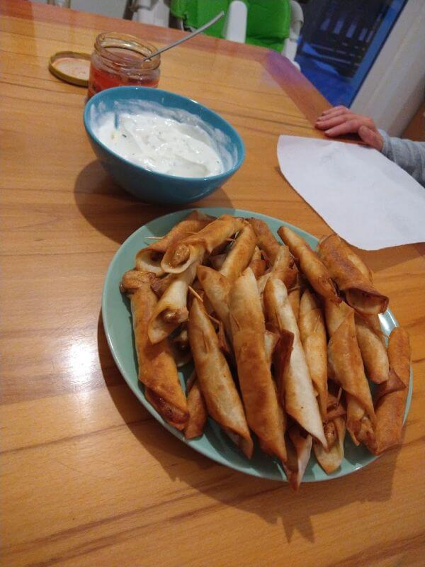 Plate of taquitos with white and red dip in the background